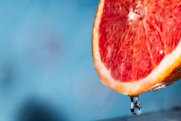 water drips from half a grapefruit. Splashes and drops fly from a piece of grapefruit symbolizing the brightness and freshness of its taste