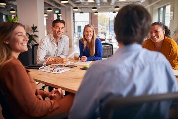 Business Team Having Meeting Sitting Around Table In Modern Open Plan Office