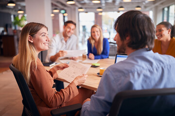 Business Team Having Meeting Sitting Around Table In Modern Open Plan Office