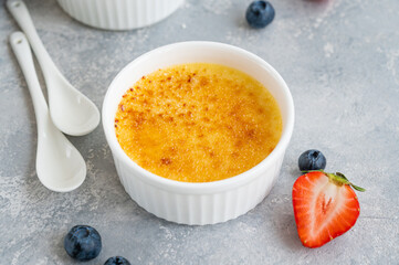 Creme brulee. Traditional French vanilla cream dessert with caramelised sugar and fresh berries on top.