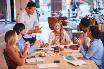 Colleagues Celebrating Businesswoman's Birthday At Meeting Around Table  In Modern Open Plan Office