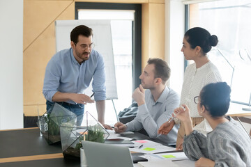 Diverse colleagues employees team with leader brainstorming, gathering in boardroom, coworkers discussing financial documents, project results statistics, involved in briefing, sitting at table