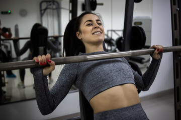 Young female athlete work out in gym performing chest exercise.