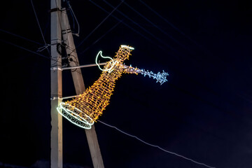 Illuminated angel sculpture attached to an electric pole glows in the dark. Creative modern...