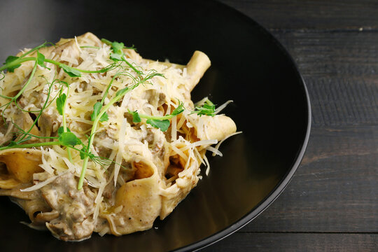 alfredo pasta with beef, chease and microgreen closeup on wooden table