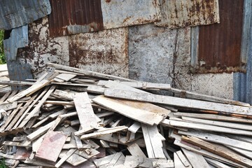 Pile of discarded planks and boards in front of funky rusted metal wall abstract horizontal architecture background