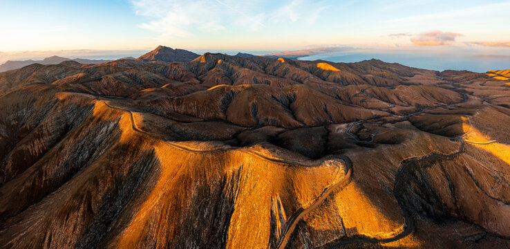 Empty road crossing the barren mountains of Pajara at dawn from Sicasumbre observatory, Fuerteventura, Canary Islands