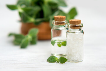 Spa and wellness setting with sea salt, oil essence, jasmin flowers and towels on wooden background. Relax and treatment therapy.