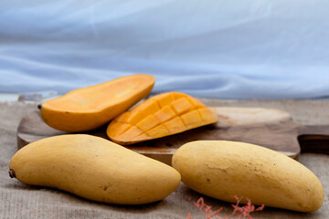 Tropical fruit mango and slice mango put on wooden tray white cloth background.