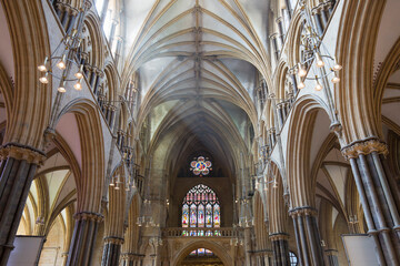 View along sunlit nave to the colourful stained glass Great West Window of Lincoln Cathedral, Lincoln, Lincolnshire, England, United Kingdom