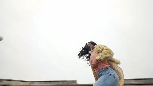 Energetic black woman dancing on concrete border