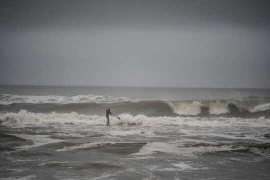 Man trying to get out through big shorebreak on his stand up paddle board, Nags Head, North Carolina