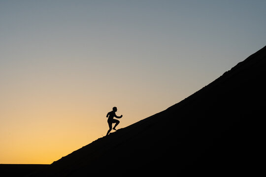 Silhouette of a man running up a sand dune in Nags Head, North Carolina - Powered by Adobe