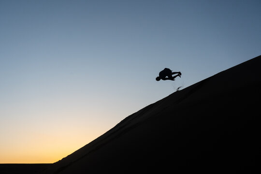 Silhouette of a man tumbling down a sand dune in Nags Head, North Carolina