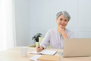 Senior Asia woman working from home using laptop and smart phone. Old woman living and learning online.
