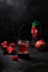 Glass of pomegranate juice and fresh fruits on against black background, space for text. Splashing juice
