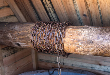 Metal chain in a wooden well for lifting a bucket of water, close-up. Traditional © HENADZY