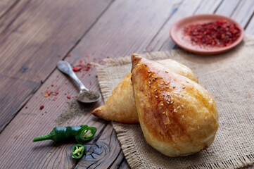 Delicious Uzbek Samsa with lamb and spices cooked in tandoor on wooden background. Uzbek and...