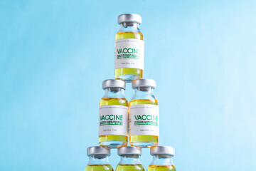 Vials of coronavirus vaccine doses are arranged in a pyramid on a blue background. Vaccine research and development concept covid-19,