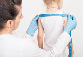 The doctor measures the width of the child's shoulders, development and growth with a measuring tape. Measurement of anthropometric data