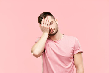 Tired disappointed young man with face palm gesture over pink background