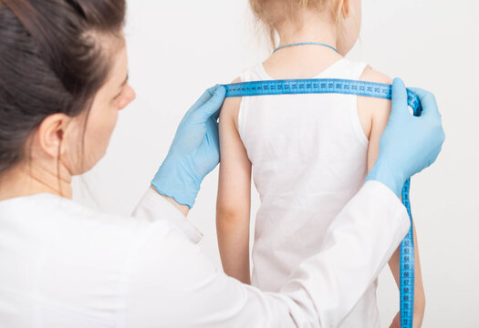 The doctor measures the width of the child's shoulders, development and growth with a measuring tape. Measurement of anthropometric data