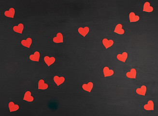 Pattern from red hearts on a black wood background with copy space