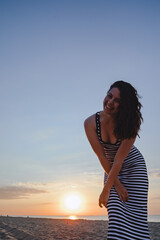 Obraz premium young beautiful sexy woman in dress walking bay sandy beach at sunset