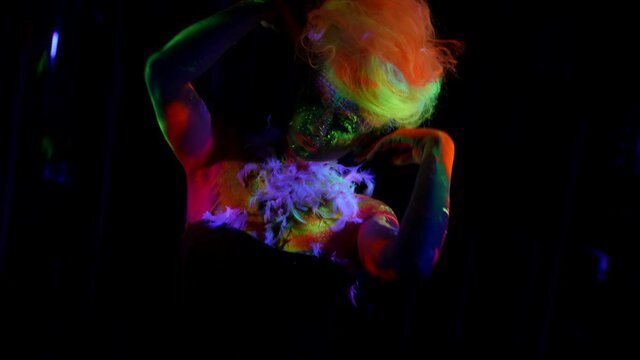 lady with eccentric makeup by fluorescent paints and neon wig on head, UV light