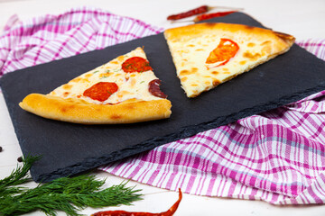 Two slices of pizza on a black serving board.