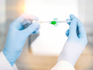 Doctor's hands hold a medical instrument cannula for veins against the background of a window with the sun. Concept of complex surgical operations, X-ray surgery