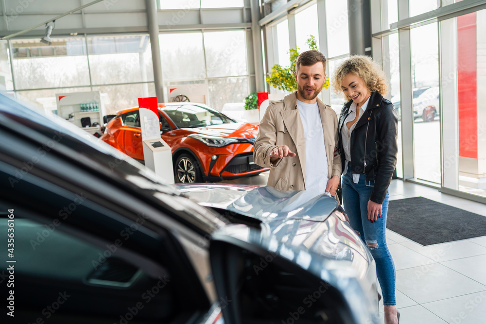 Wall mural Beautiful couple in car dealership chooses car