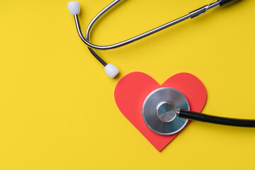Doctor stethoscope and heart symbol on yellow background. Medical concept