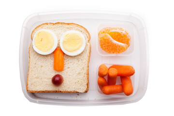 School lunch box snacks for kids over white background. Back to school. Healthy and fun snacks options for parents. Food art creative concepts. Bows with fruits and vegetables and cute face sandwich.
