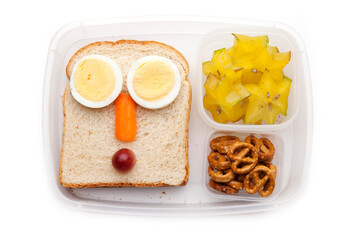 School lunch box snacks for kids over white background. Back to school. Healthy and fun snacks options for parents. Food art creative concepts. Bows with fruits and vegetables and cute face sandwich.