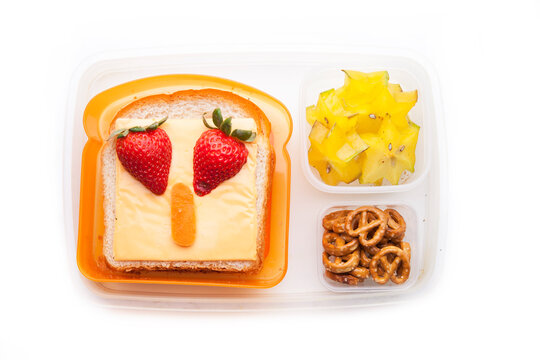 School lunch box snacks for kids over white background. Back to school. Healthy and fun snacks option for parents. Cute food art creative concepts. Bows with fruits and vegetables and cute sandwich.