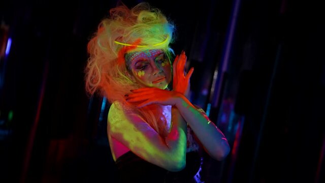 actress with fluorescent makeup and hairstyles, woman in UV light in darkness
