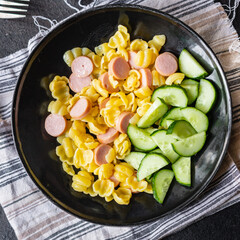 pasta sausages, cucumber salad vegetables, conchiglie menu on the table healthy food children's menu meal snack copy space food background rustic. top view