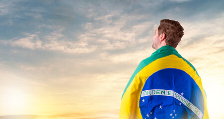 Brazilian man with Brazilian flag looking at the horizon - obrazy, fototapety, plakaty