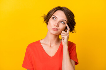 Photo of charming young girl finger on temple look interested empty space isolated on yellow color background