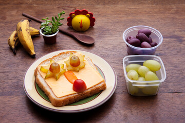 School lunch box snacks for kids over wooden background. Back to school. Healthy and fun snack option for moms. Cute food art creative concepts. Bow with fruits and vegetables and cute sandwich.