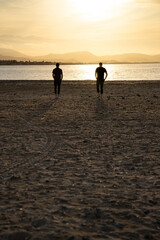 Fototapeta na wymiar Two men walking towards the sea water. At sunset. They walk apart.