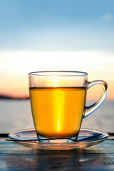 Cup of green tea front of at sunset light on wooden tabletop.