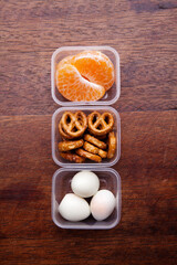 School lunch box snacks for kids over wooden background. Back to school. Healthy and fun snacks options for moms. Cute food art creative concepts. Bows with fruits and vegetables.