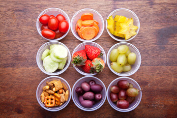 School lunch box snacks for kids over wooden background. Back to school. Healthy and fun snacks options for moms. Cute food art creative concepts. Bows with fruits and vegetables.