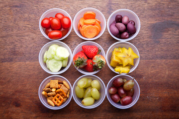 School lunch box snacks for kids over wooden background. Back to school. Healthy and fun snacks options for moms. Cute food art creative concepts. Bows with fruits and vegetables.