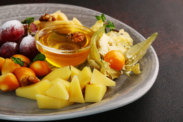 cheese plate with grape, physalis, honey and nuts close up