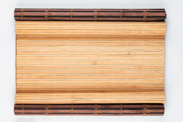 Dark and light bamboo rug with curled edges. View from above.