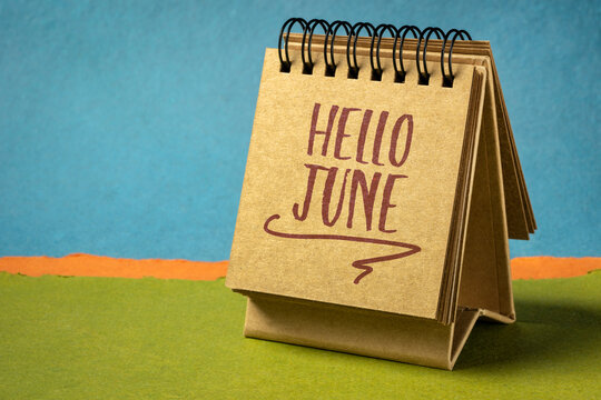 Hello June - handwriting in a desktop calendar against abstract paper landscape, cheerful greetings
