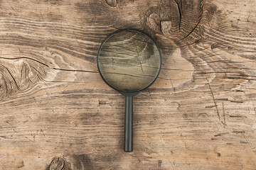 Magnifying glass on old wooden board. Top view.